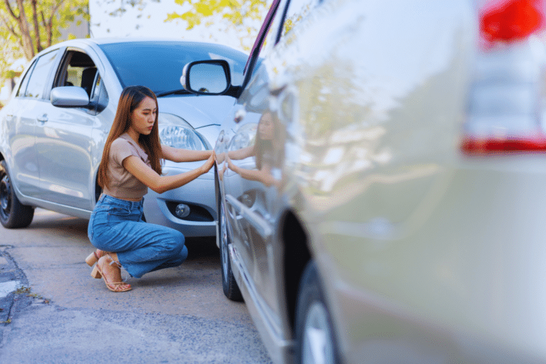 A lady checking a dent on her car