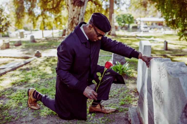 A man putting a rose flower on a tomb