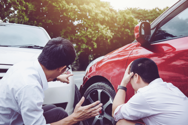 Two men by their cars looking distressed after an auto accident